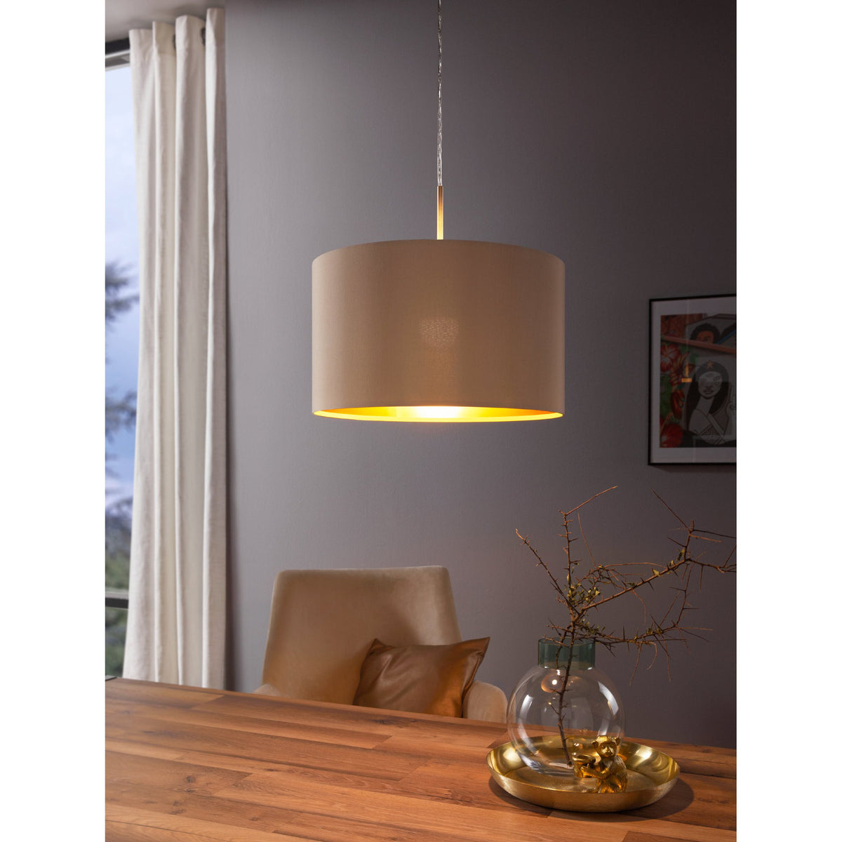 Hasanne fabric pendant light with taupe drum shade and gold interior lining, satin nickel ceiling canopy, shown above a dining table in a grey-walled room.