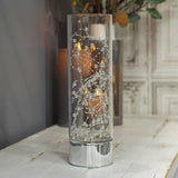 Beaded Glass LED Tube Light-Up Decoration, 30.5cm, with lit silver beads and wire inside a clear glass cylinder on a mirror-finish silver base, shown on a table in a living room setting.