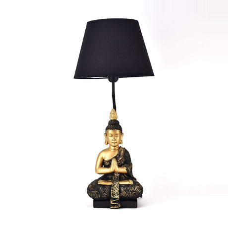 Praying Buddha Table Lamp 46cm in black and gold, featuring a seated figure with hands pressed together on a square base and a tapered black shade, set against a plain white background.