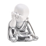 Buddha cherub figurine with chin resting on hand, seated smiling pose in white and silver finish, robe draped over crossed legs, on a plain white background.