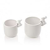 Set of two round white ceramic planters in different sizes, each with a small bunny perched on the rim, finished in glossy white glaze on a plain background.