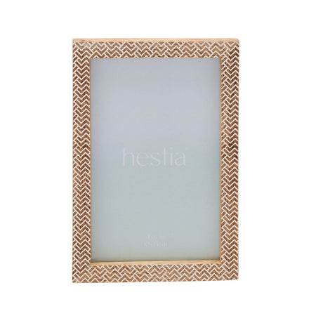 Wooden photo frame with a brown and white chevron stamped pattern bordering the rectangular opening, holds a 6 x 4in print, shown on a white background.