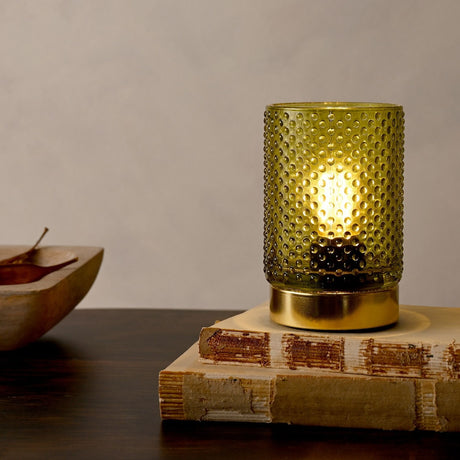 Glass Cup Table Lamp with LED Bulb Light in green hobnail-textured glass on a gold base, lit and displayed on a book beside a wooden bowl.