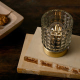 Glass Cup Table Lamp with LED bulb lit inside, faceted diamond-pattern glass shade on a round gold base, shown on a book beside a wooden tray.