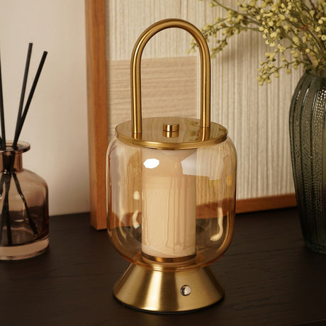Lantern USB LED touch table lamp with gold loop handle, lid and flared base, amber-tinted glass shade with lit white column, shown on a dark tabletop.