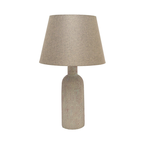 Slim ribbed bottle ceramic table lamp in beige with a weathered, flecked finish and tapered fabric shade, shown on a plain white background.