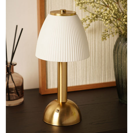 USB LED touch table lamp with a ribbed white bell shade, gold cap and knop, slim brushed gold stem and domed base, shown on a dark table beside a vase.