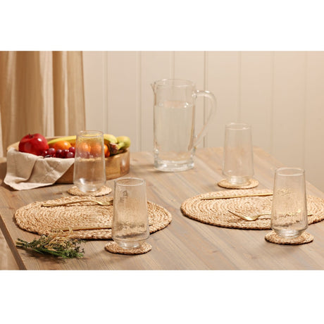 Tapered Hammered Style Highball Glass Tumblers in clear glass with woven coasters, placemats, and a matching jug, styled on a dining table with fruit and cutlery.