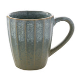 Tapered fluted stoneware mug with a speckled green glaze, lighter sage near the rim deepening to grey-green at the base, shown with a curved handle on a plain white background.