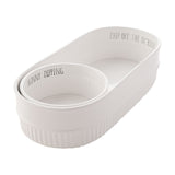 White fluted stoneware chip and dip bowl set with oval base reading "Chip Off The Ol' Block" and round insert reading "Skinny Dipping", ribbed sides, plain background.