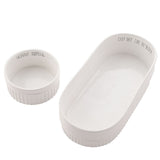 Set of 2 fluted white stoneware chip and dip bowls, an oval dish reading "Chip Off The Ol' Block" with a round "Skinny Dipping" bowl inside, on a plain background.
