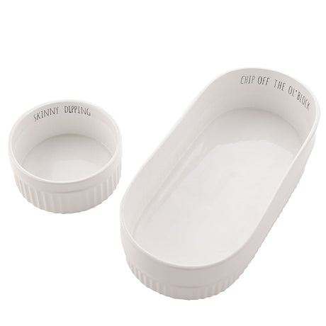Set of 2 fluted white stoneware chip and dip bowls, an oval dish reading "Chip Off The Ol' Block" with a round "Skinny Dipping" bowl inside, on a plain background.