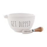 White glazed round stoneware bowl with handle, lettered "GET DIPPED" in black, paired with a wooden-handled spreader reading "SPREAD THE LOVE" on a plain white background.