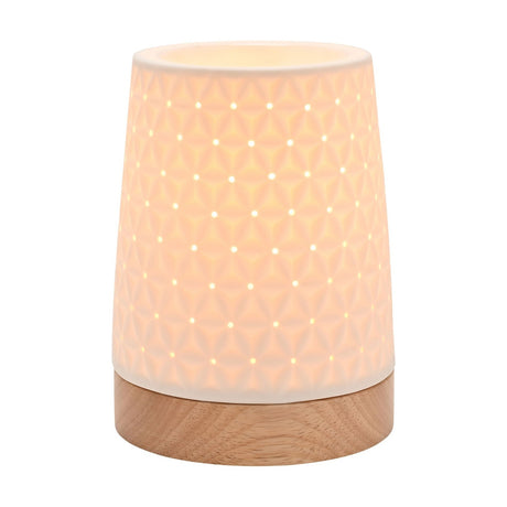 White ceramic tapered table lamp, 15cm, with embossed star pattern and pierced holes, lit from within, set on a round wooden base against a white background.