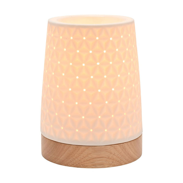 White ceramic tapered table lamp, 15cm, with embossed star pattern and pierced holes, lit from within, set on a round wooden base against a white background.