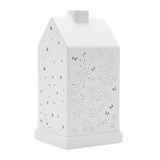 White ceramic table lamp shaped like a house with pitched roof and chimney, cut-out butterflies and floral stems on front, stars on sides, 20.5cm, plain background.