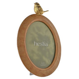 Oval wood effect resin photo frame in brown with a gold bird perched on top, holding a 5x7in photo, shown on a white background.