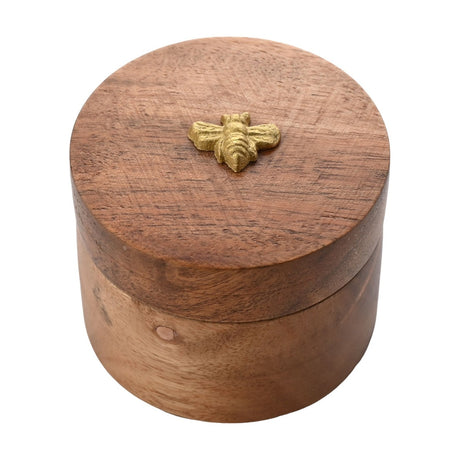 Round acacia wood salt box storage jar in natural brown with visible grain, featuring a gold-coloured bee emblem on the lid, shown on a white background.