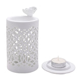 White round ceramic wax melt burner with cut-out lattice pattern and a butterfly on the rim, shown with a round white tealight holder and tealight candle on a plain background.