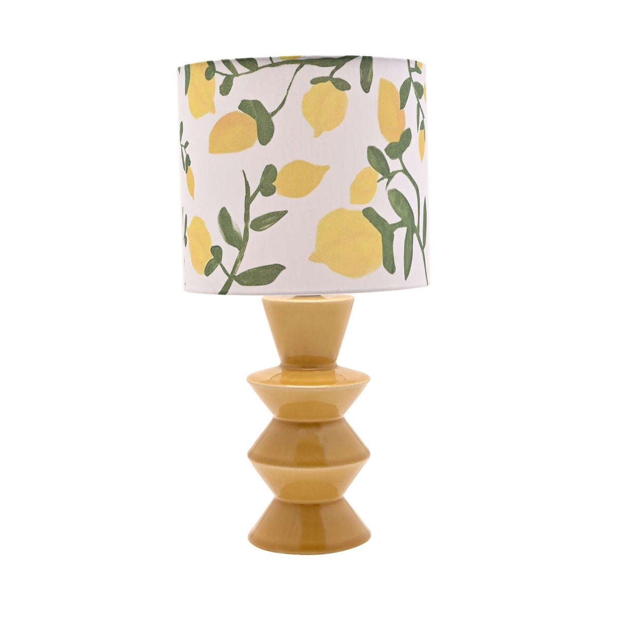 Ceramic table lamp with a glossy yellow stacked tiered base and white drum shade printed with lemons and green leaves, shown on a plain white background.