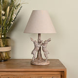Wood Effect Hare Table Lamp with Natural Shade 46cm in Brown, featuring two boxing hares flanking a tree trunk base with a tapered fabric shade, shown on a wooden sideboard.