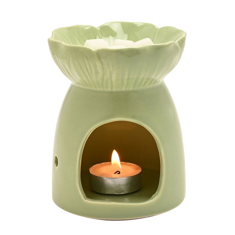 Green ceramic flower-shaped wax melt burner with a petal-textured dish holding wax cubes, lit tealight visible through the cut-out base, on a plain white background.