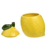Lemon-shaped earthenware sugar storage jar in yellow with dimpled peel texture, shown open with its lid featuring a glossy green leaf handle, on a plain white background.