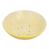 Round earthenware serving bowl designed as a lemon slice, with textured yellow peel-effect exterior and pale yellow segmented interior dotted with brown pips, on a plain white background.
