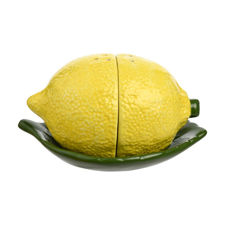 Lemon-shaped earthenware salt and pepper shaker set in yellow with dimpled peel texture and green stalks, resting on a matching green leaf-shaped dish on a white background.