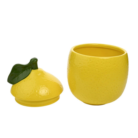 Lemon-shaped yellow earthenware storage jar with dimpled citrus-textured body, shown open beside its lid topped with a green leaf and stalk, on a plain white background.