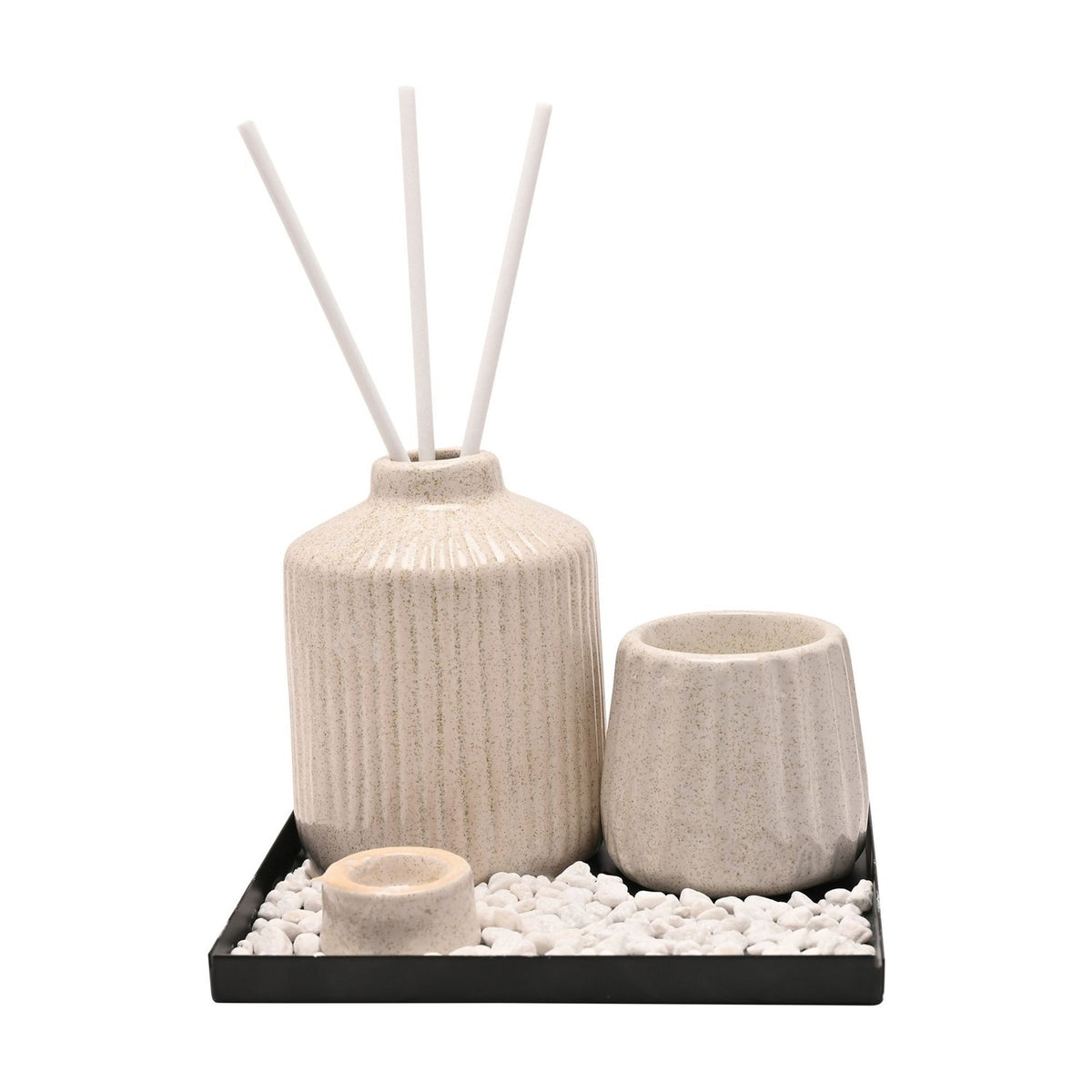 Ribbed ceramic diffuser vessel set in off-white with three white reeds, a ridged pot and small cup on a black tray with white pebbles, shown on a plain white background.