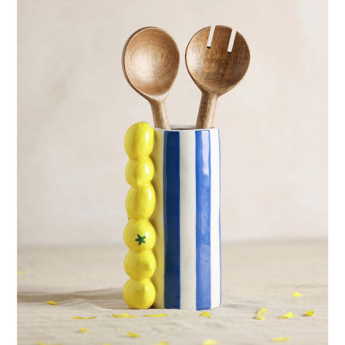 Lemon Ceramic Vase with Stripes 21cm in Blue, a cylindrical vase with blue and white stripes and moulded yellow lemons, holding two wooden serving spoons on a plain background.