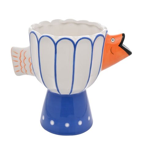 White ceramic pedestal vase with fluted cobalt-outlined panels, a scalloped rim, orange fish head and tail details, and a blue flared foot with white dots.