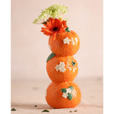 Stacked ceramic vase with three glossy orange dimpled spheres, white blossoms, and green leaf details, 21cm, holding orange and white flowers against a plain light background.