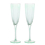 Set of two scallop stemmed champagne flutes in pale green glass with panelled bowls, slim stems and round flat feet, shown against a plain white background.