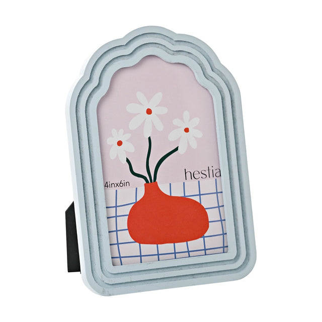 Scalloped arched wooden photo frame in pale blue with stepped tiered layers, holding a 6 x 4in portrait photo, shown at an angle against a plain white background.