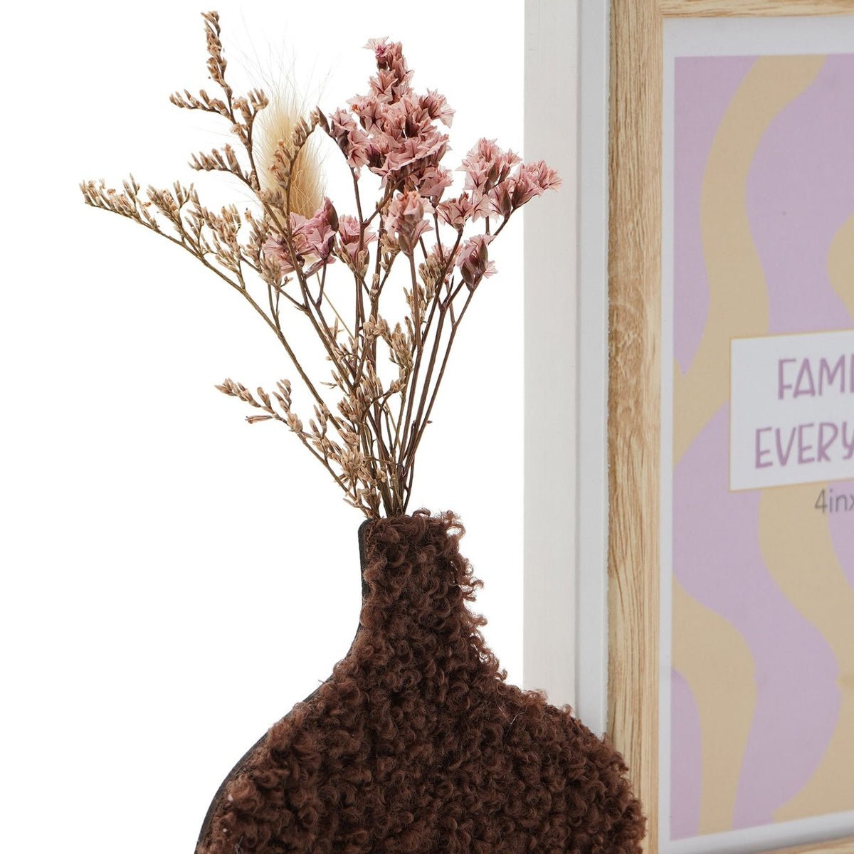 Close-up of the dark brown textured vase with dried pink flowers and grasses beside a wooden photo frame with white edge, 6 x 4in, holding a "Family Everyday" print.