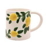 White ceramic mug with a C-handle, featuring raised yellow lemons on green leafy sprigs winding around the body, shown on a plain white background.