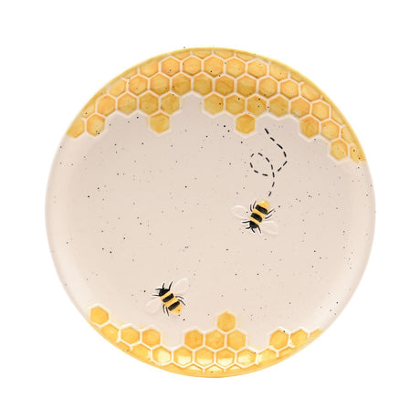 Round earthenware plate in cream with raised yellow honeycomb borders top and bottom, two striped bees and a dashed flight path across the centre, on a plain white background.