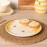 Round earthenware plate, 20.7cm, cream glaze with raised yellow honeycomb edges and bee motifs, shown with mince pies on a woven placemat.