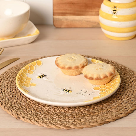 Round earthenware plate, 20.7cm, cream glaze with raised yellow honeycomb edges and bee motifs, shown with mince pies on a woven placemat.
