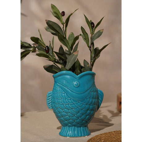 Light blue glazed stoneware vase shaped like an upright carp with raised scales, fins, and open mouth rim, holding olive branch stems on a neutral background.