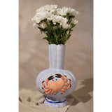 Hand-painted ceramic vase in periwinkle blue with a textured orange crab design, ribbed body, fluted scalloped neck, and blue-banded base, styled with white flowers.