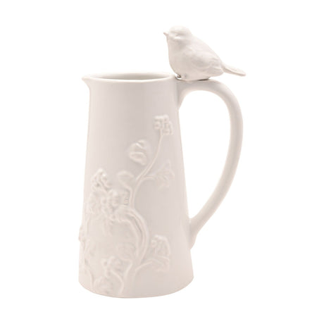 Tall white earthenware jug with raised floral vine pattern, curved handle, and a small bird perched on top, shown on a plain background.