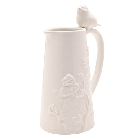 Tall white earthenware jug, 710ml, with a tapering body, raised floral and berry design on one side, a looped handle, and a small bird perched on top, set against a plain white background.