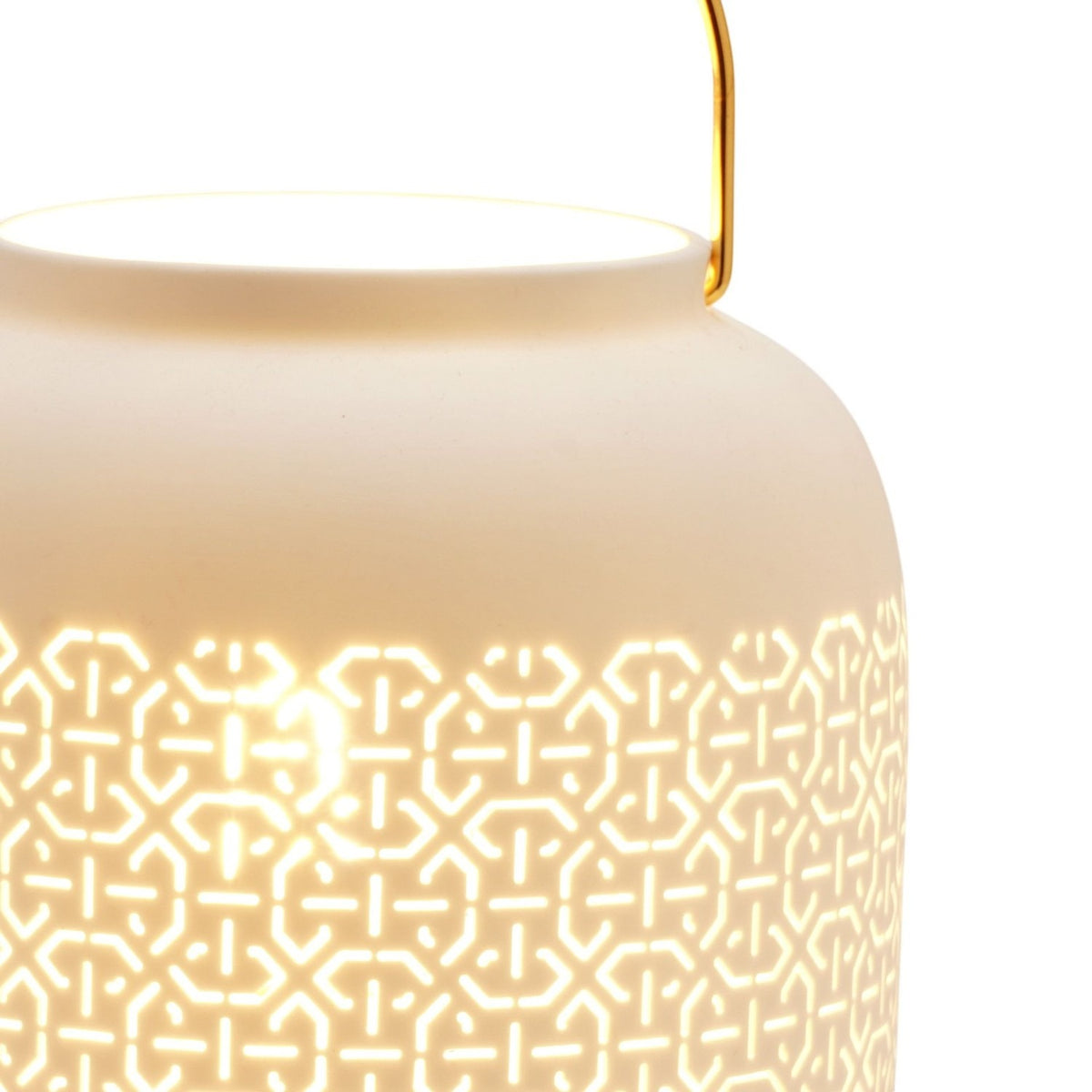 Close-up of the Abstract Pattern Porcelain Lantern Table Lamp in white, showing the cut-out geometric lattice glowing from within and the curved gold handle.
