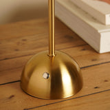 Close-up of the Pleated Shade USB LED Touch Table Lamp's brushed bronze dome base and slim stem with touch control, set on a wooden surface near books.