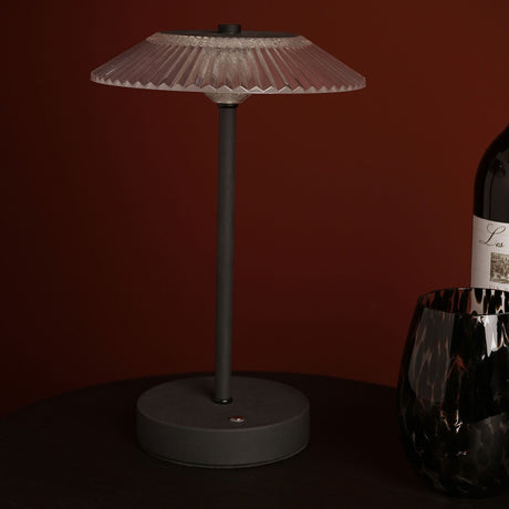 Ribbed Glass USB LED Touch Table Lamp with clear fluted shade, slim black stem and round black base, shown on a dark table beside a wine bottle and glass.