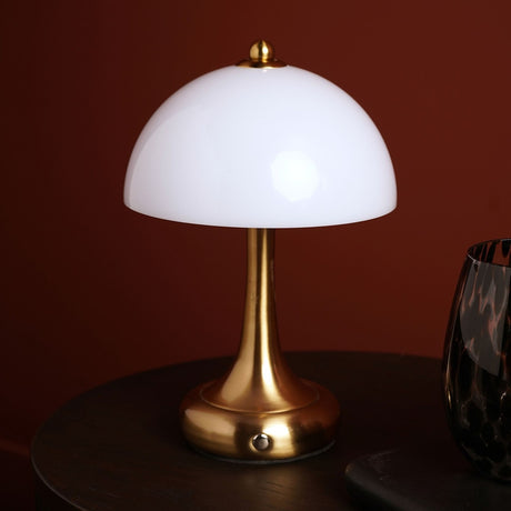 Domed USB LED Touch table lamp with opaque white glass shade and bronze stem, finial, and round base, shown lit on a dark table beside a glass vase.
