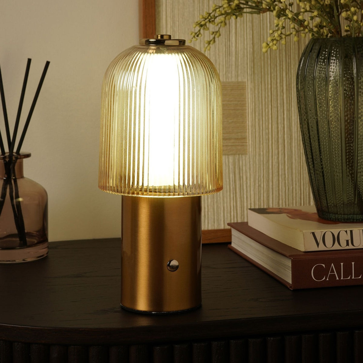 Ribbed Dome USB LED Touch Table Lamp in bronze and champagne, lit on a dark sideboard with a touch button on the cylindrical base, styled beside books and a vase.